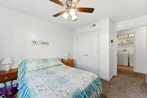 Bedroom featuring a closet, dark carpet, ceiling fan, and washing machine and dryer
