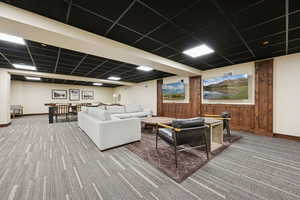 Carpeted living room with baseboards and a paneled ceiling