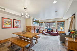 Dining space featuring a fireplace, stone finish flooring, recessed lighting, and a chandelier