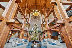 Common area featuring high vaulted ceiling, a wooden ceiling with exposed beams, stairway, and wooden walls