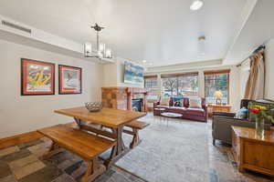 Dining space featuring a fireplace, stone tile floors, recessed lighting, and a chandelier