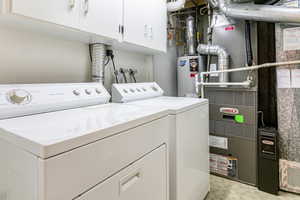 Features a laundry chute from 3rd floor!Washroom with cabinet space, heating unit, water heater, and washing machine and clothes dryer