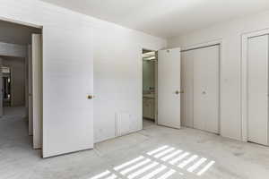 Unfurnished bedroom with multiple closets, ensuite bath, and carpet flooring