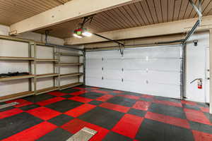 Garage featuring a garage door opener and wooden ceiling and man door