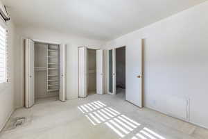 Unfurnished bedroom with light carpet and two closets