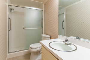 Full bath featuring wallpapered walls, vanity, a stall shower, tile patterned floors, and crown molding