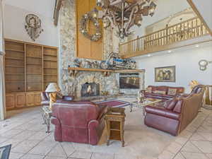 Living room with a fireplace, light tile patterned floors, and a towering ceiling