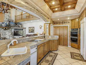 Kitchen featuring brown cabinets, tile counters, light tile patterned floors, recessed lighting, and built in fridge