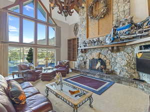 Carpeted living area with high vaulted ceiling and a fireplace