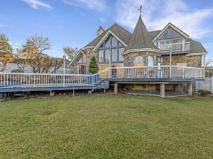 Back of property featuring stone siding, a deck, a yard, and a chimney