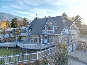 Back of property featuring stone siding, a wooden deck, and a shingled roof