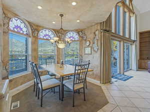 Tiled dining room with a chandelier and recessed lighting