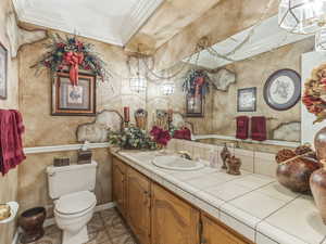 Half bath with ornamental molding, vanity, and light tile patterned flooring