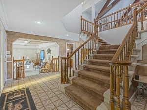 Stairs with recessed lighting, beam ceiling, ornamental molding, arched walkways, and coffered ceiling