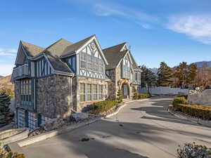 View of front of property with stone siding, a mountain view, roof with shingles, and stucco siding