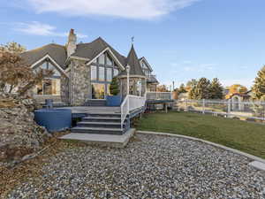 Rear view of house with stone siding, a chimney, and a wooden deck