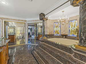 Full bathroom with vanity, a garden tub, ornamental molding, and a chandelier