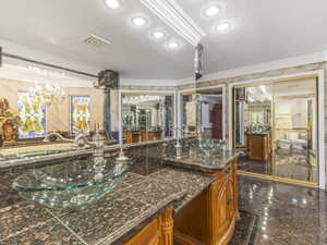 Bathroom with ornamental molding, double vanity, granite floors, a chandelier, and recessed lighting