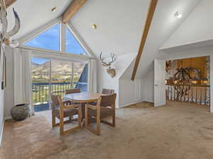 Dining room featuring beamed ceiling, light colored carpet, a mountain view, and high vaulted ceiling