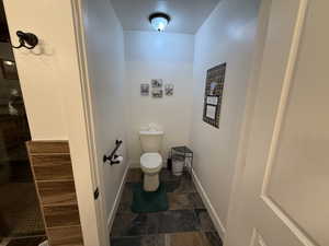 Bathroom featuring dark stone finish floors and a tile shower