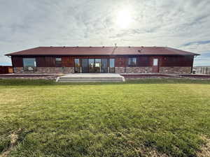 Back of property with stone siding, a yard, and a patio area