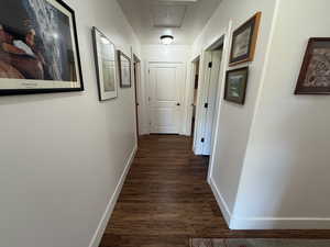 Corridor featuring baseboards and dark wood-style floors