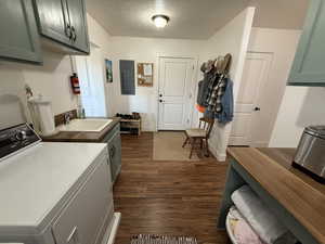 Laundry area with washer / clothes dryer, a textured ceiling, cabinet space, dark wood finished floors, and electric panel
