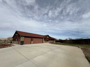 View of property exterior with stone siding, driveway, and an attached garage