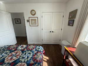 Bedroom with dark wood-style floors and a closet