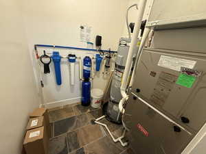 Utility room featuring heating unit and gas water heater.  Water filer system
