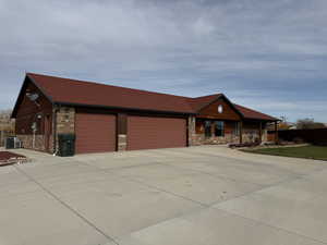 Ranch-style house with stone siding, driveway, a garage, and covered porch
