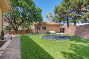 Fenced backyard featuring a trampoline, a patio area, and an outdoor living space