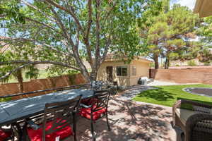 Fenced backyard featuring an outbuilding, outdoor dining space, a patio area, and a grill