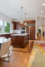 Kitchen with pendant lighting, light wood-style floors, paneled built in refrigerator, recessed lighting, and double oven