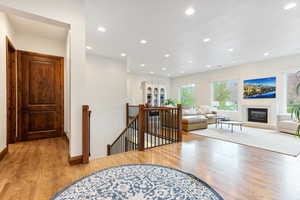 Hallway with an upstairs landing, recessed lighting, and light wood-type flooring