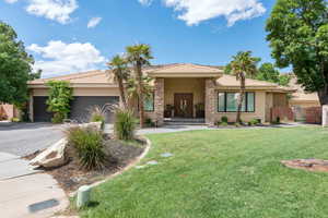Prairie-style house with a front yard, stucco siding, a garage, decorative driveway, and a porch