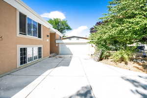 View of side of property featuring stucco siding, a garage, and driveway