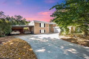 View of front of house featuring driveway, stucco siding, a garage, and a carport