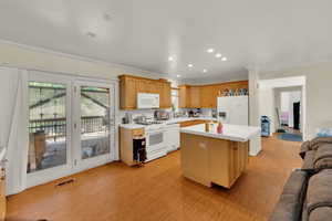 Kitchen featuring tile counters, white appliances, a kitchen island, light wood finished floors, and crown molding