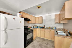 Kitchen featuring light brown cabinetry, freestanding refrigerator, black electric range, and decorative backsplash