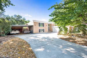 View of front of house with stucco siding, driveway, a garage, and an attached carport