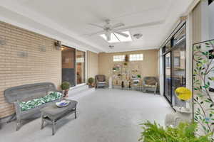 Sunroom featuring a ceiling fan and a patio