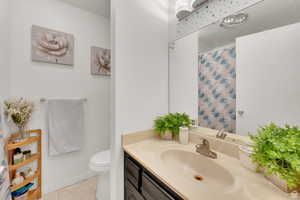 Bathroom with curtained shower, vanity, and light tile patterned floors