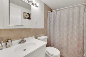 Bathroom featuring vanity, a shower with curtain, tile walls, and a textured ceiling