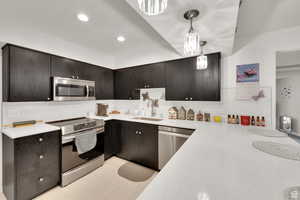Kitchen with stainless steel appliances, hanging light fixtures, recessed lighting, light stone countertops, and modern cabinets