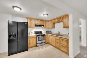 Kitchen featuring appliances with stainless steel finishes, light countertops, light brown cabinets, under cabinet range hood, and light tile patterned flooring