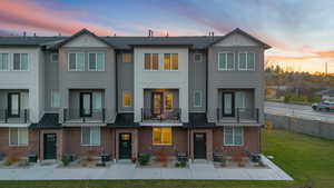Rear view of property featuring a balcony, a lawn, brick siding, and board and batten siding