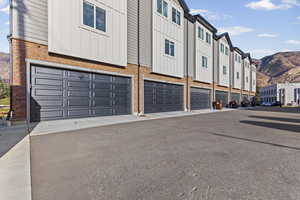 Exterior space with board and batten siding, an attached garage, a mountain view, brick siding, and asphalt driveway