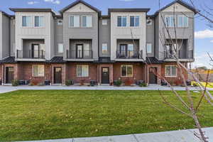 View of front facade with brick siding, a balcony, and a standing seam roof