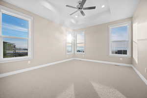 Spare room featuring carpet, a tray ceiling, recessed lighting, and ceiling fan